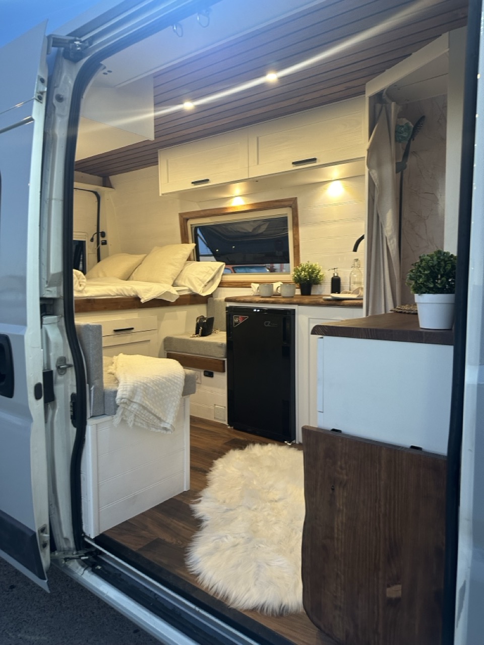 Interior de la camper con la cama, la zona de estar y la cocina